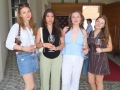 Vier junge Frauen mit Weingläsern stehen in einem Innenhof vor einem Gebäude in Österreich.